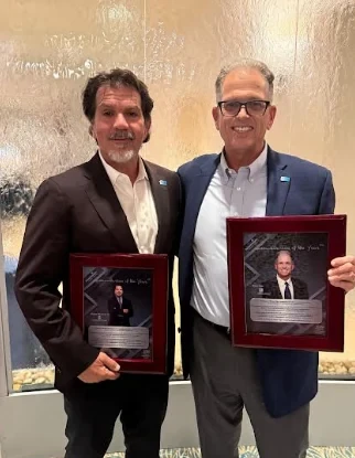 Michael D. Chiumento III and Bruce Page holding their 2026 Humanitarian of the Year awards on PalmCoastLocal.com.